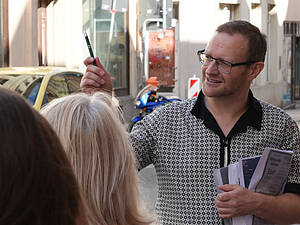 Heimatforscher Christian Repkewitz mit Unterlagen unter dem linken Arm und einem Stift in der rechten Hand spricht zu Exkursionsteilnehmenden.