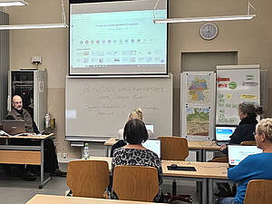 Kursraum mit Dozent und Teilnehmenden.