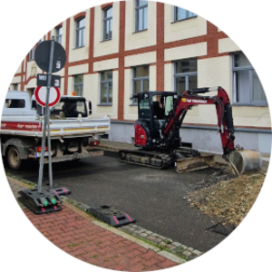 Bagger und Lastkraftwagen auf der Straße vor der Volkshochschule Schmölln.