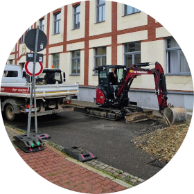 Bagger und Lastkraftwagen auf der Straße vor der Volkshochschule Schmölln.